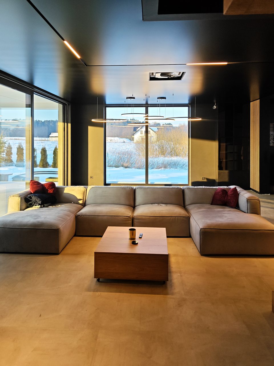 Narożna sofa w salonie pod czarnym satynowym sufitem napinanym