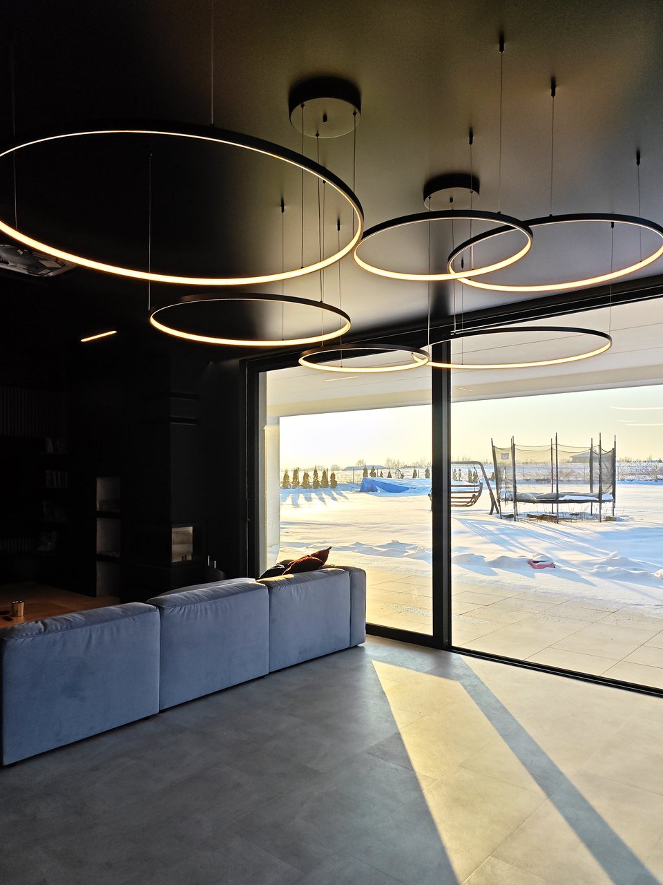 Lampy ring zawieszone pod czarnym sufitem napinanym w strefie jadalnianej