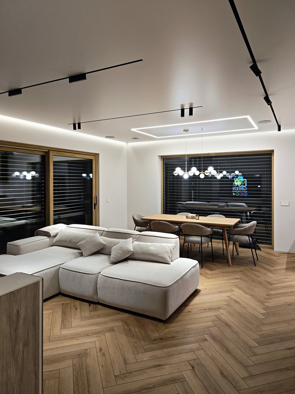 Otwarty salon z jadalnią pod białym sufitem napinanym z prostokątną linią LED